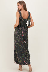 woman wearing a black floral print maternity dress with ruffled straps and a tiered skirt, showing her pregnant belly