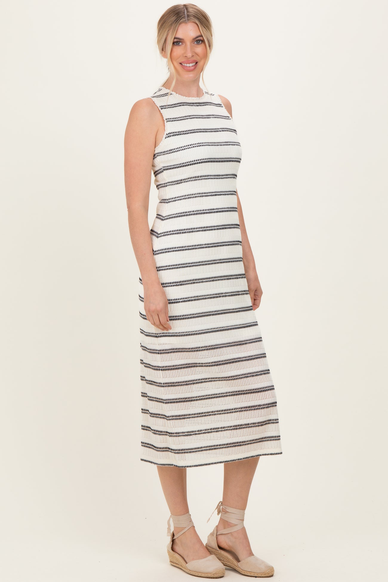woman wearing a striped sleeveless midi dress with a halter neck and a relaxed fit, standing in espadrille wedges