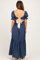 woman wearing a navy blue maternity dress with puff sleeves and a bow detail at the back