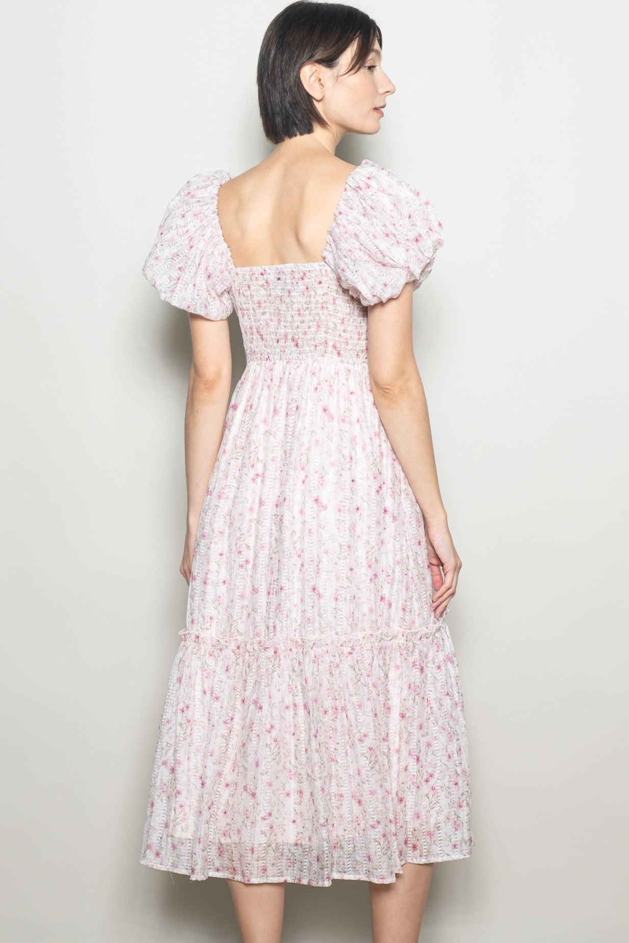 woman wearing a floral midi dress with puff sleeves and a smocked bodice, seen from the back