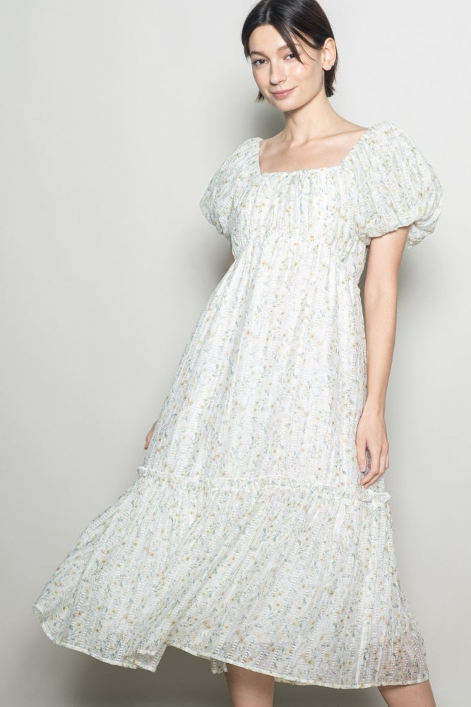 woman wearing a light floral print midi dress with puff sleeves and a tiered hem