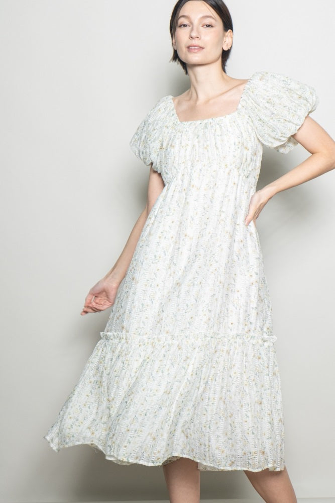 woman wearing a white floral midi dress with puff sleeves and a tiered skirt