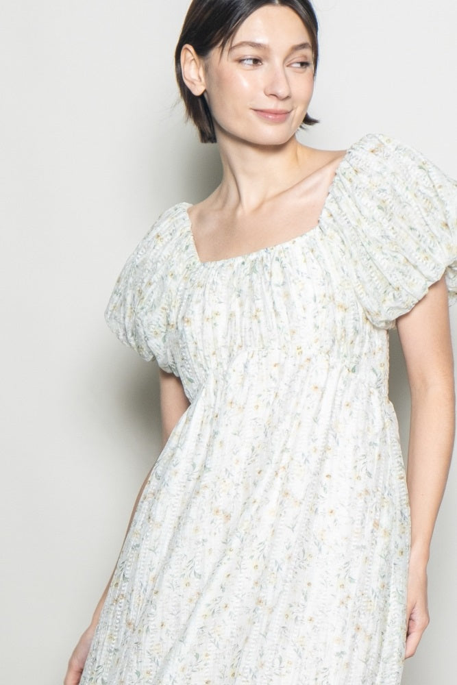 woman wearing a light floral print puff sleeve dress with a square neckline