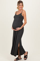woman wearing a black and gray striped maternity maxi dress with side slits and holding her baby bump