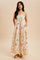 woman wearing a yellow floral maxi dress with pockets and spaghetti straps, standing against a neutral background
