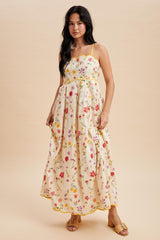woman wearing a cream floral maxi dress with spaghetti straps and ruffle hemline, styled with sandals