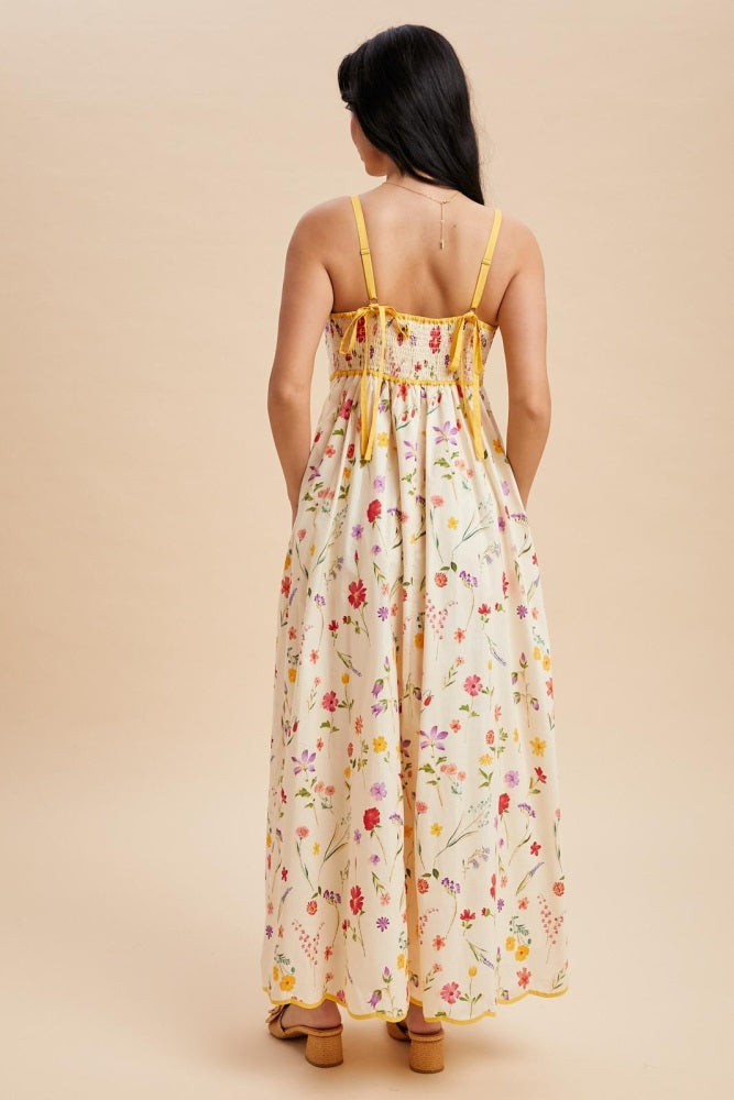 woman wearing a floral maxi dress with a smocked back and yellow straps, standing against a neutral background