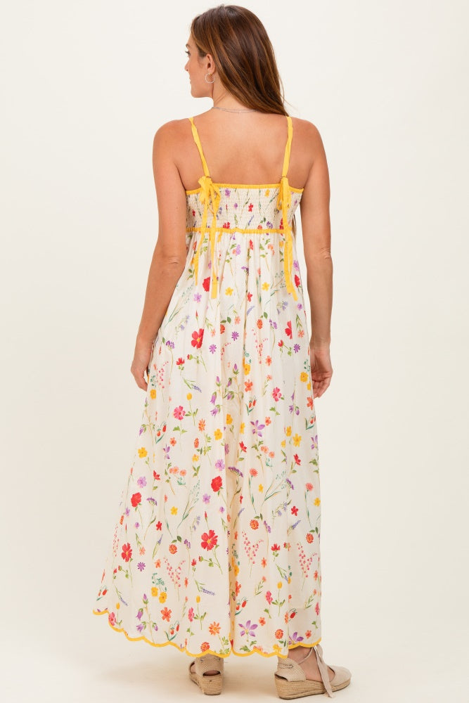 woman wearing a white floral maxi dress with yellow straps and a smocked back design