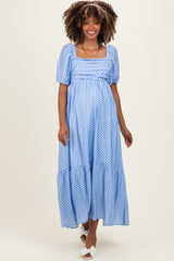 woman wearing a light blue polka dot maternity dress with puff sleeves and a tiered skirt, highlighting her baby bump