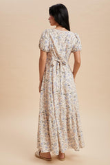 woman wearing a floral maxi dress with short puff sleeves and a tie-back detail, shown from the back