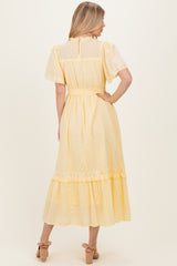 woman wearing a yellow midi dress with short sleeves, a fitted waist, and a tiered ruffle hem