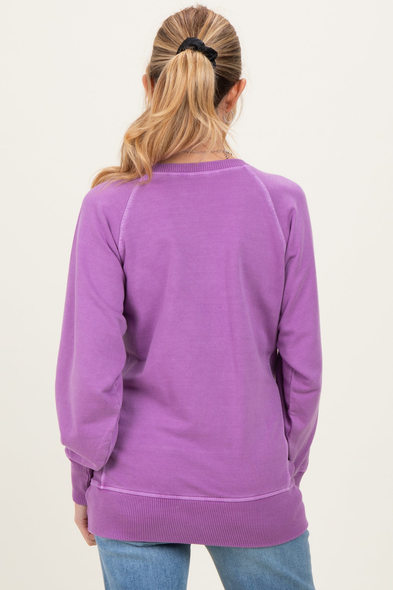 woman wearing a light purple maternity sweatshirt, seen from the back with a relaxed fit and ribbed hem