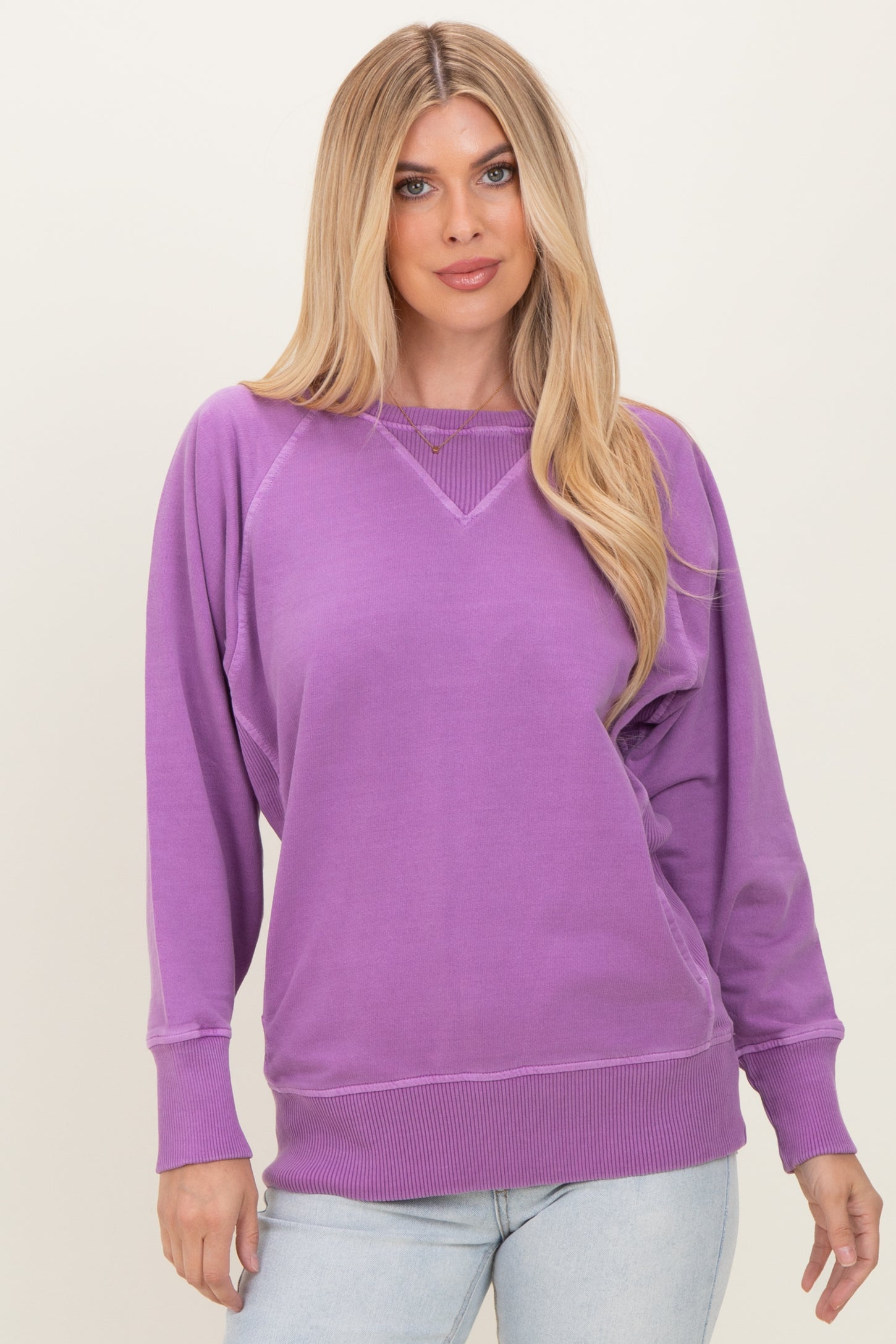woman wearing a purple oversized sweatshirt with a wide neckline and ribbed cuffs