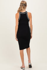 woman wearing a black maternity dress with white trim, showing a fitted silhouette and a knee-length hem