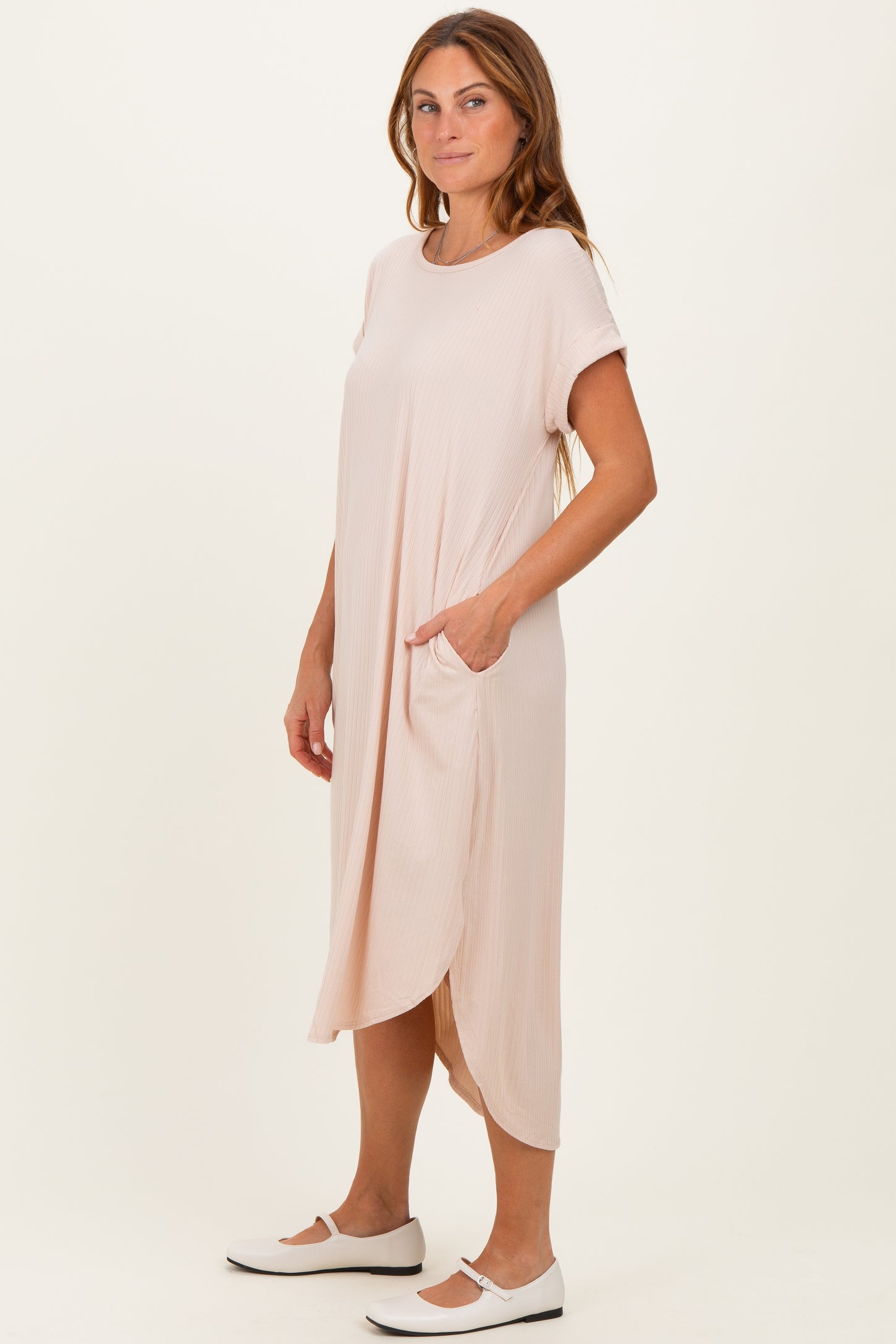 woman wearing a light pink short sleeve midi dress with pockets and a relaxed fit
