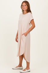 woman wearing a light pink short sleeve midi dress with pockets and a relaxed fit