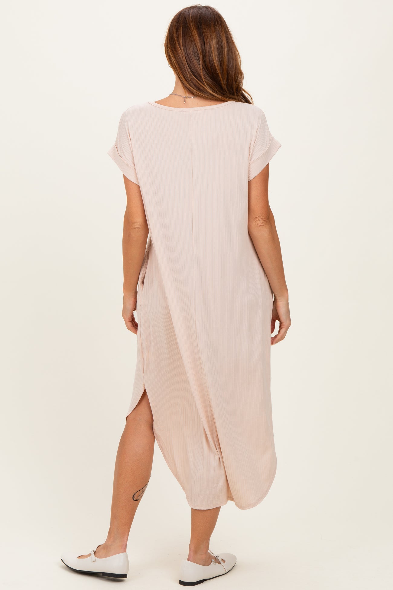 woman wearing a light pink maxi dress with short sleeves and side slits, shown from the back