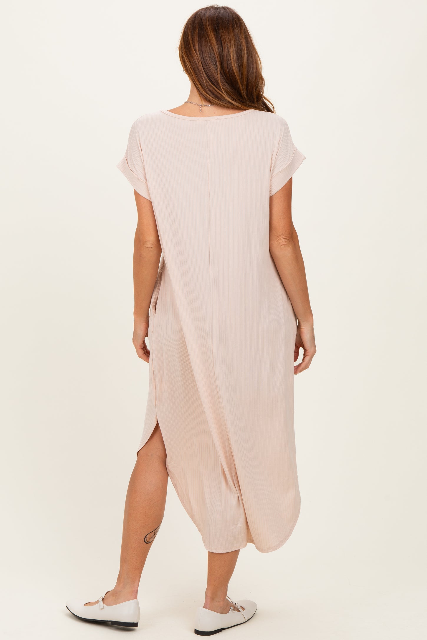 woman wearing a light pink maxi dress with short sleeves and side slits, shown from the back