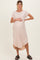 woman wearing a light pink short sleeve maternity dress with a baby bump and a high-low hemline