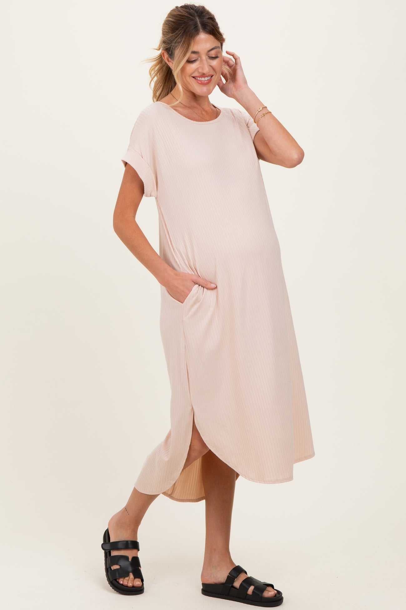 woman wearing a light pink maternity dress with short sleeves, side pockets, and a relaxed fit, showing her baby bump