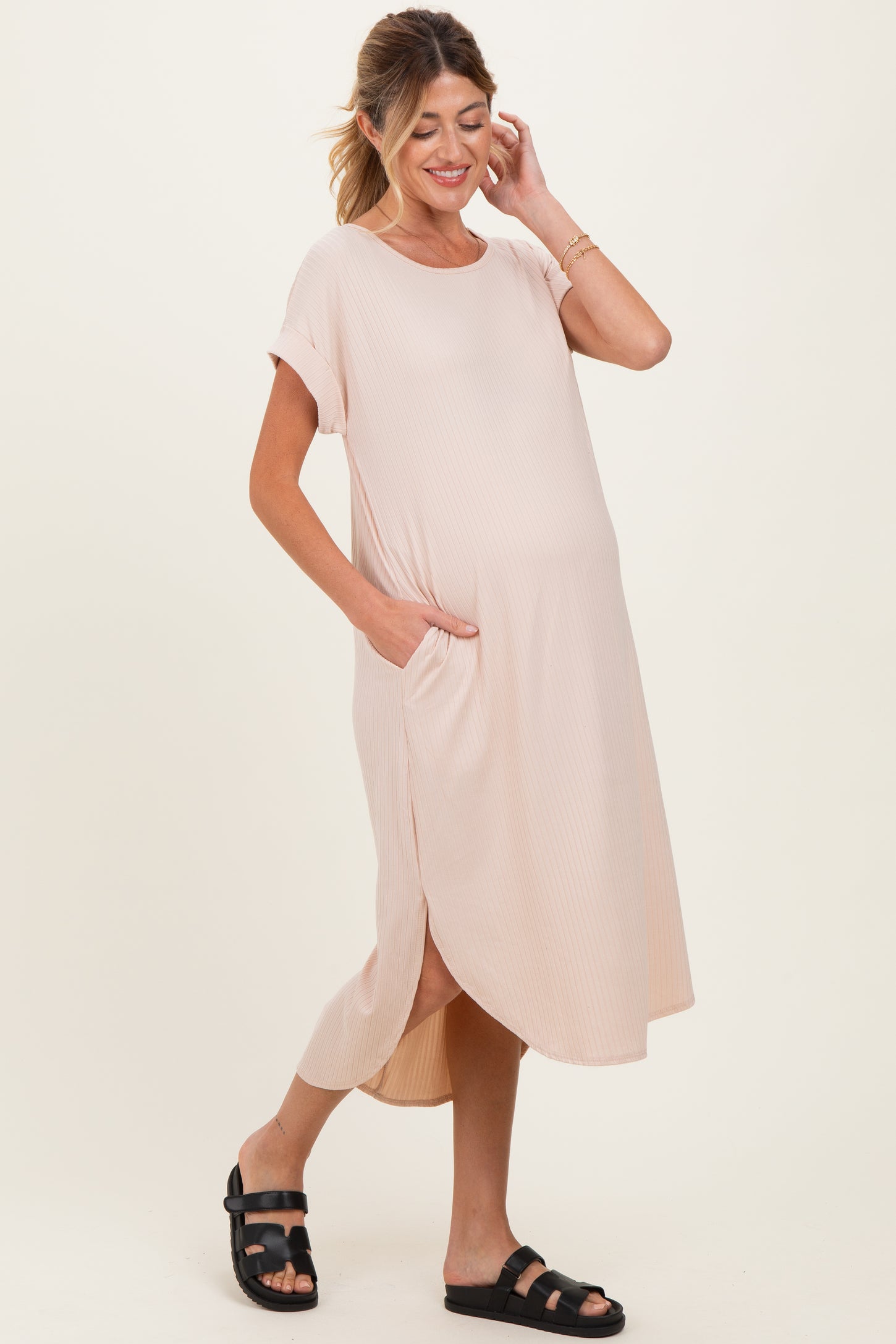 woman wearing a light pink maternity dress with short sleeves, side pockets, and a relaxed fit, showing her baby bump