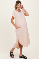 woman wearing a light pink maternity dress with short sleeves, side pockets, and a relaxed fit, showing her baby bump