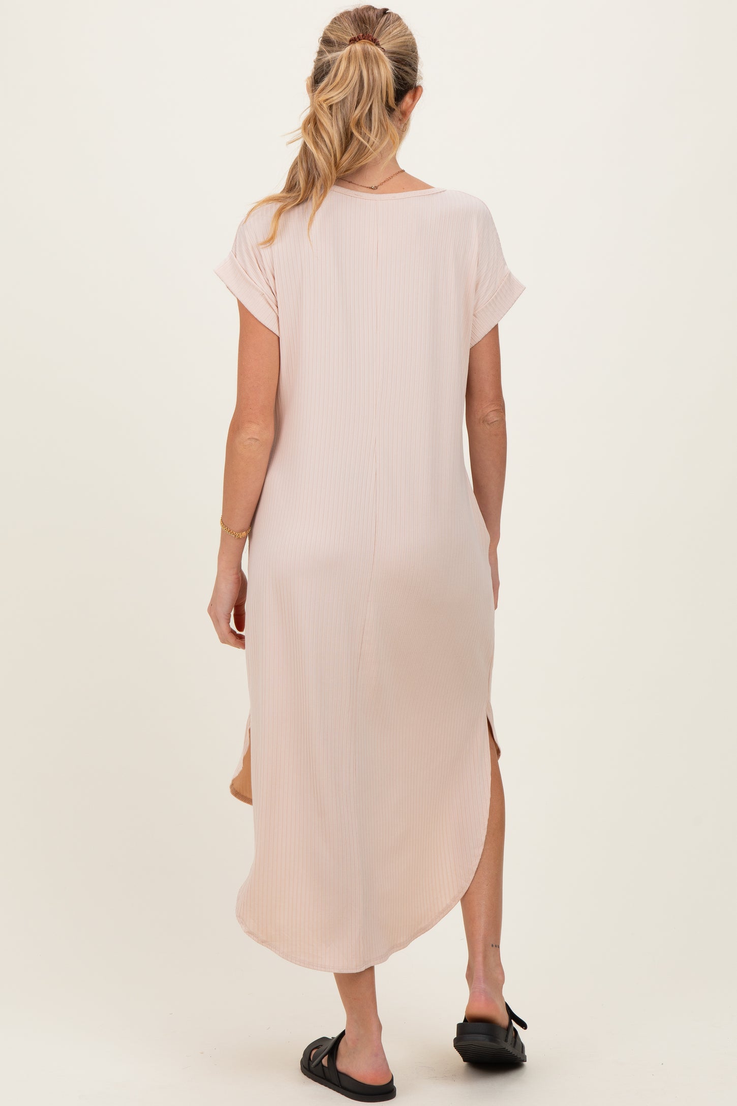 woman wearing a light pink long sleeve maternity dress with side slits, view from the back