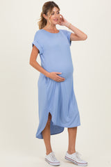 woman wearing a light blue short sleeve maternity dress with a side slit and holding her baby bump