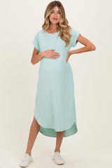 woman wearing a mint green ribbed maternity dress with a curved hem and holding her baby bump