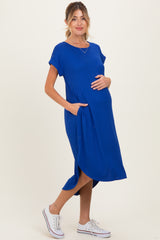 woman wearing a royal blue ribbed maternity dress with pockets and holding her baby bump