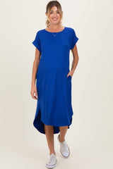 woman wearing a bright blue maternity maxi dress with short sleeves and pockets, showing her baby bump