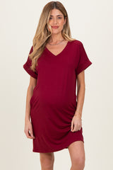 woman wearing a burgundy maternity dress with a v-neck and rolled short sleeves, showing a baby bump