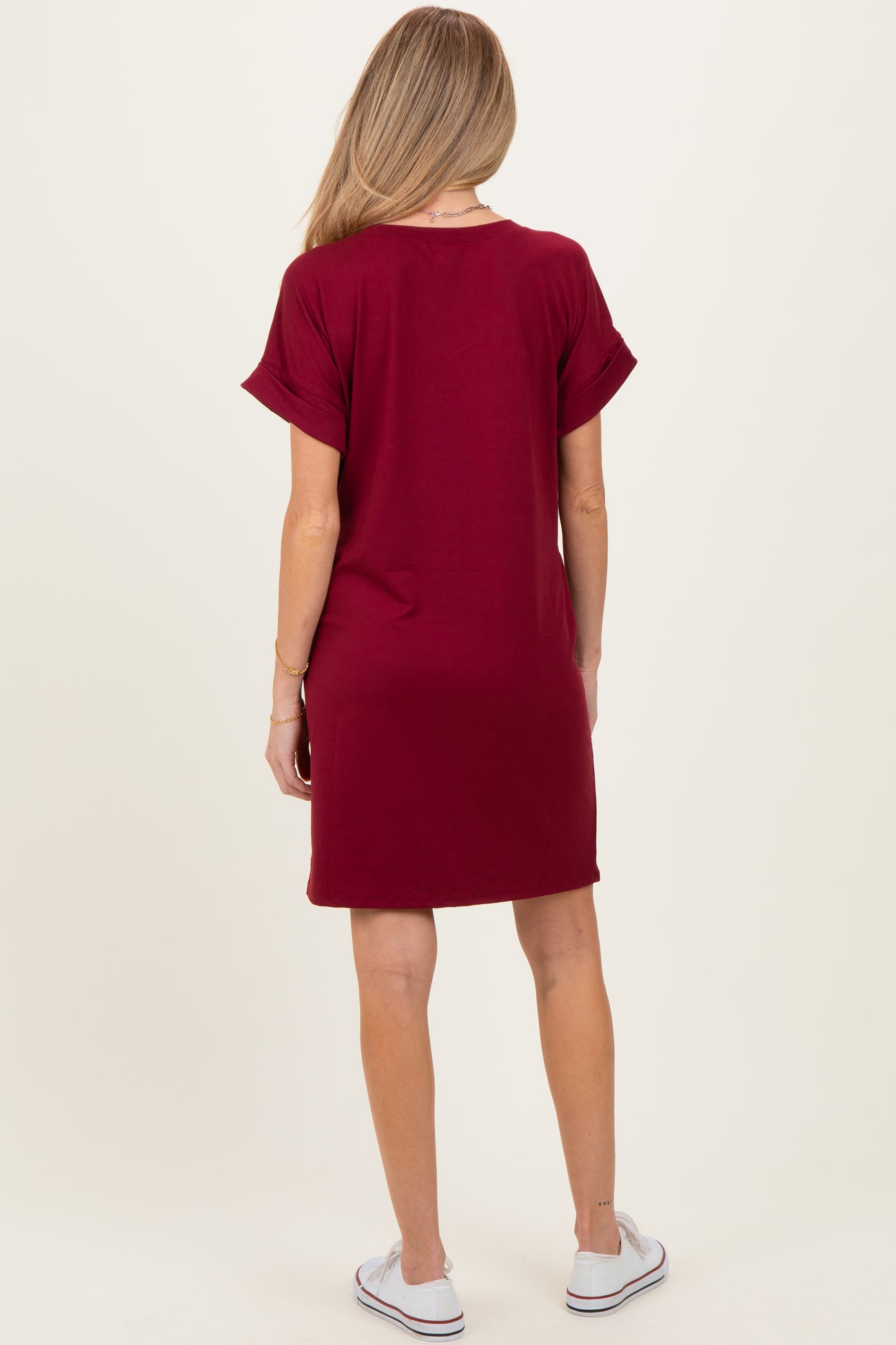 woman wearing a maroon short sleeve maternity dress, seen from the back with rolled sleeves