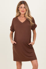 woman wearing a brown short sleeve v-neck maternity dress with side pockets and a visible baby bump