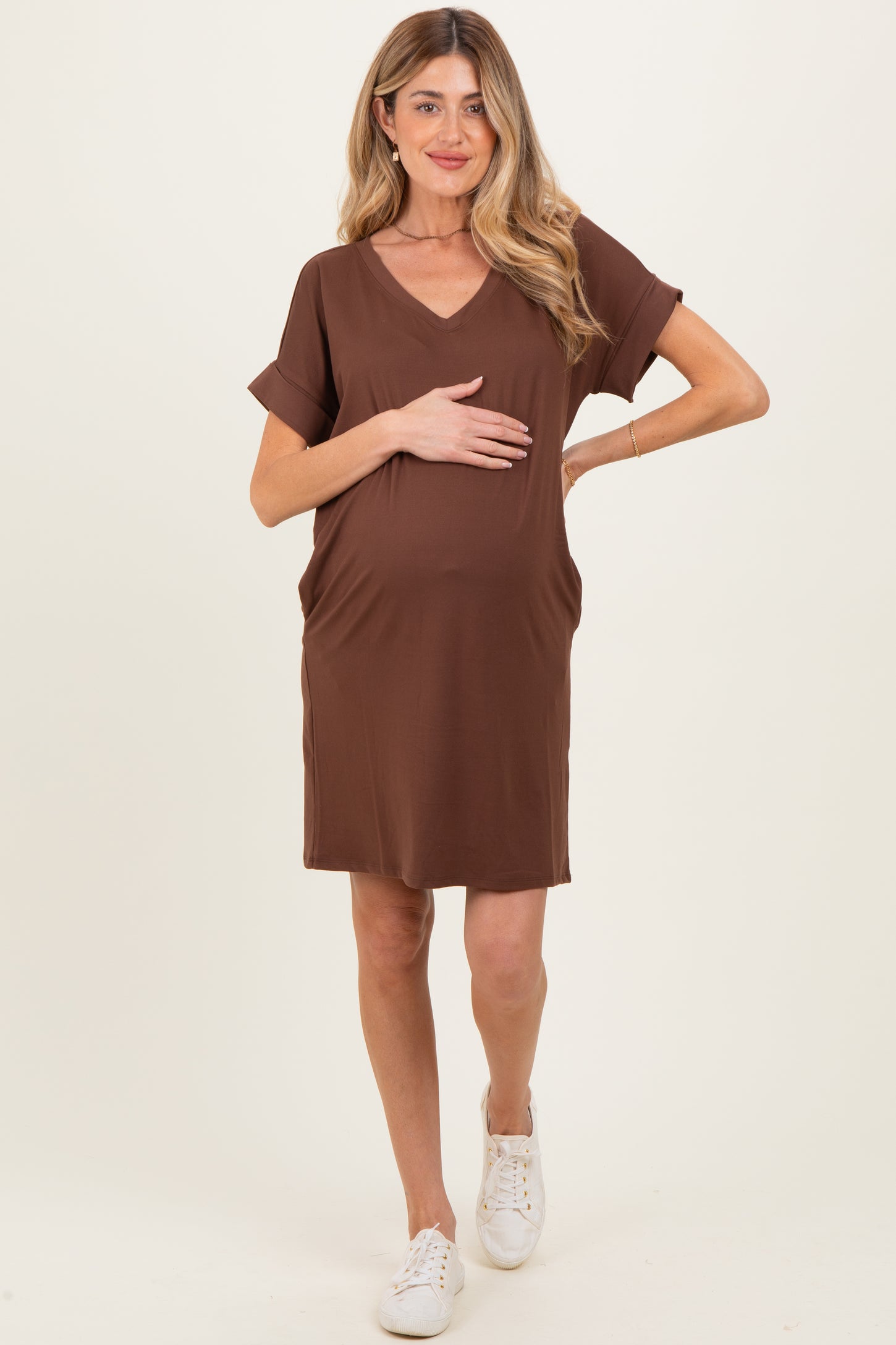 woman wearing a brown short sleeve maternity dress and holding her baby bump