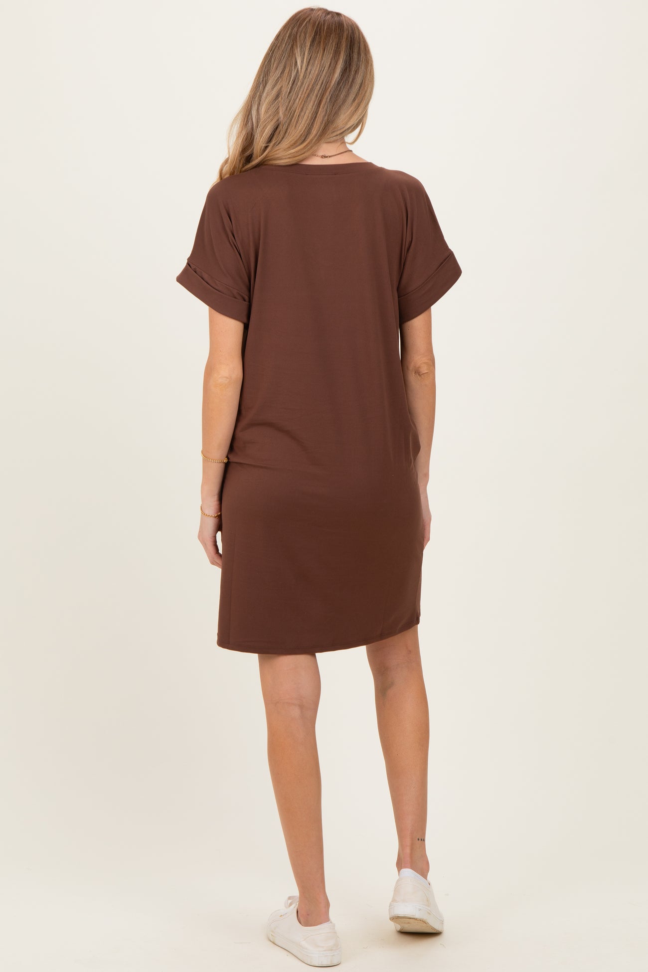 woman wearing a brown short sleeve maternity dress, seen from the back, paired with white casual shoes