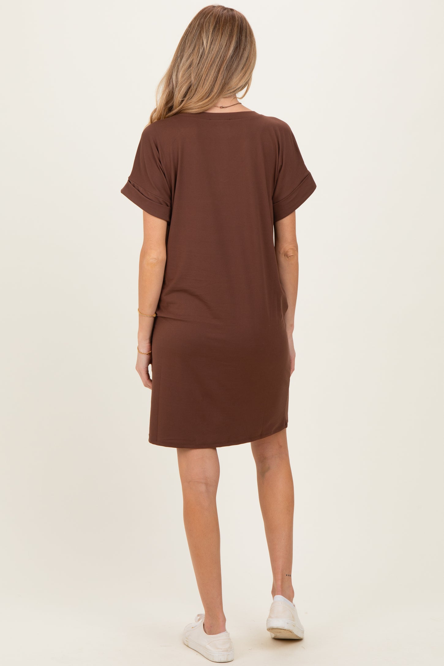 woman wearing a brown short sleeve maternity dress, seen from the back, paired with white casual shoes