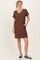woman wearing a brown short sleeve v-neck dress with pockets and black sneakers