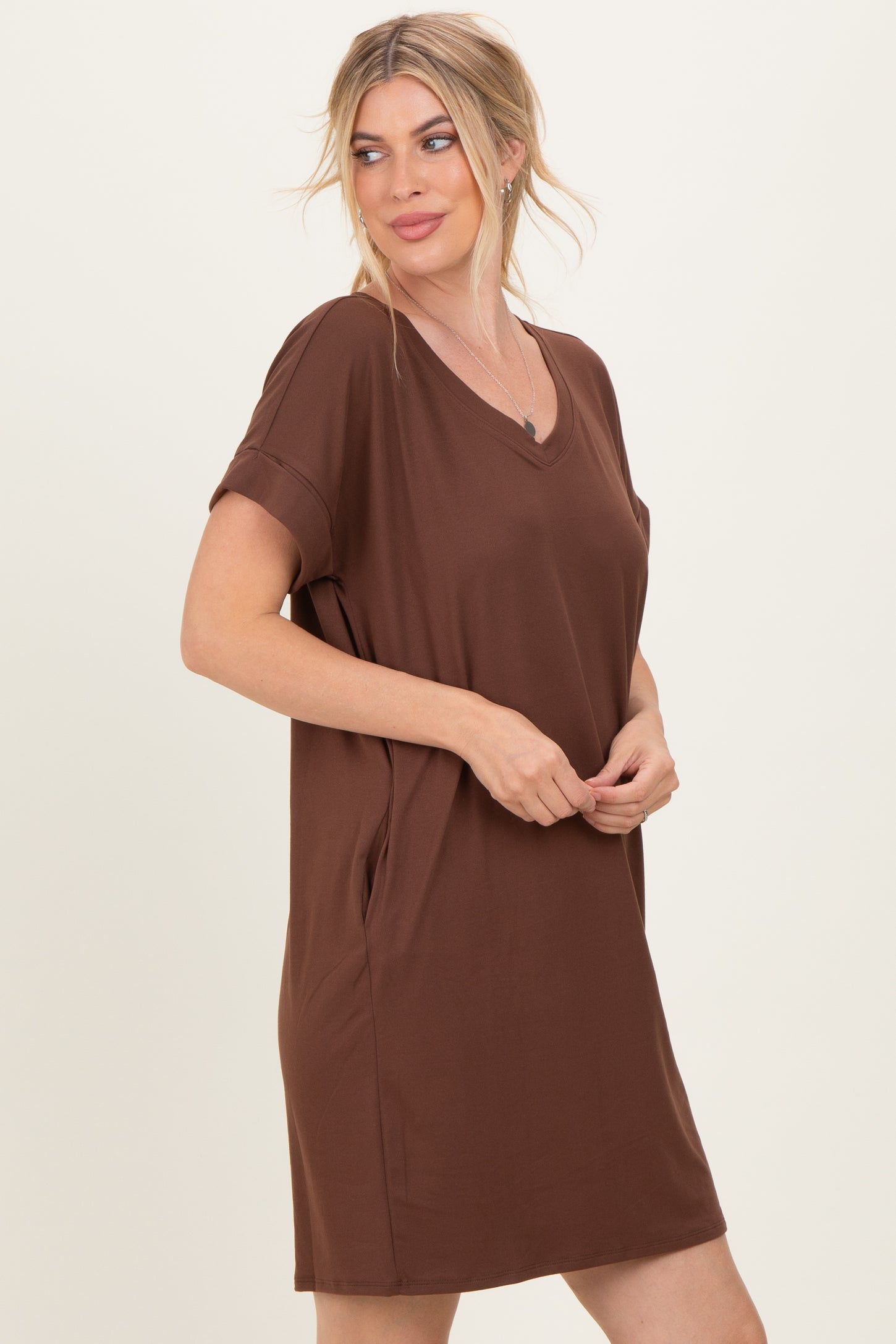 woman wearing a brown short sleeve v-neck dress with side pockets and a relaxed fit