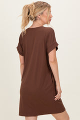 woman wearing a brown short sleeve t-shirt dress with rolled cuffs, standing with her back to the camera
