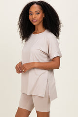woman wearing a beige oversized t-shirt with rolled sleeves and side slits, paired with beige bike shorts