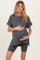 woman wearing a dark gray maternity top and matching shorts with her hands on her baby bump