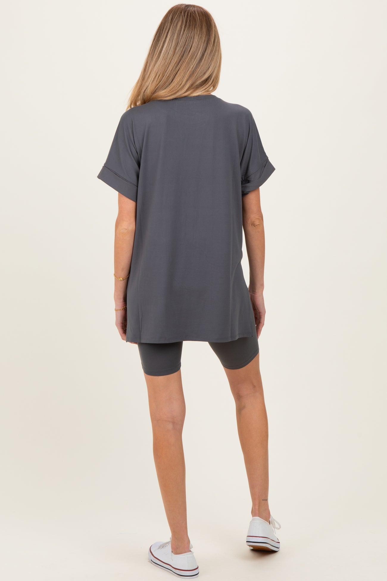woman wearing a gray maternity tunic top and matching bike shorts, facing away from the camera