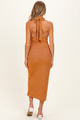 woman wearing a striped orange and yellow maternity dress with a halter neck and open back detail