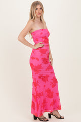 woman wearing a strapless hot pink maxi dress with red floral print and ruched detailing