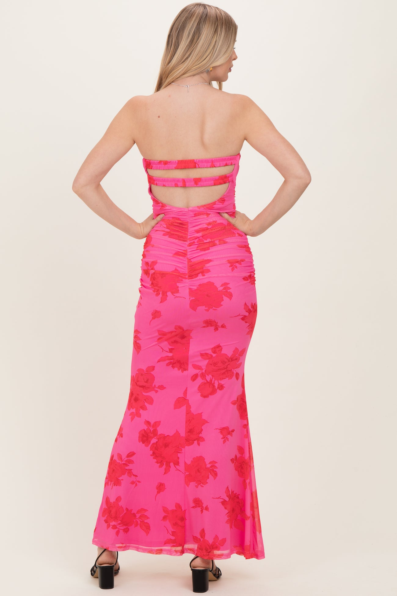 woman wearing a hot pink floral maxi dress with a back cut-out and ruching details