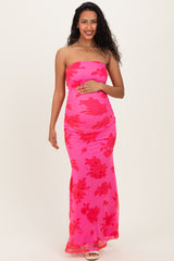 woman wearing a pink strapless maternity dress with red floral patterns and holding her baby bump