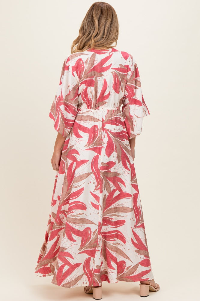 woman wearing a floral maternity maxi dress with bell sleeves, showcasing a pink and white leaf pattern from the back
