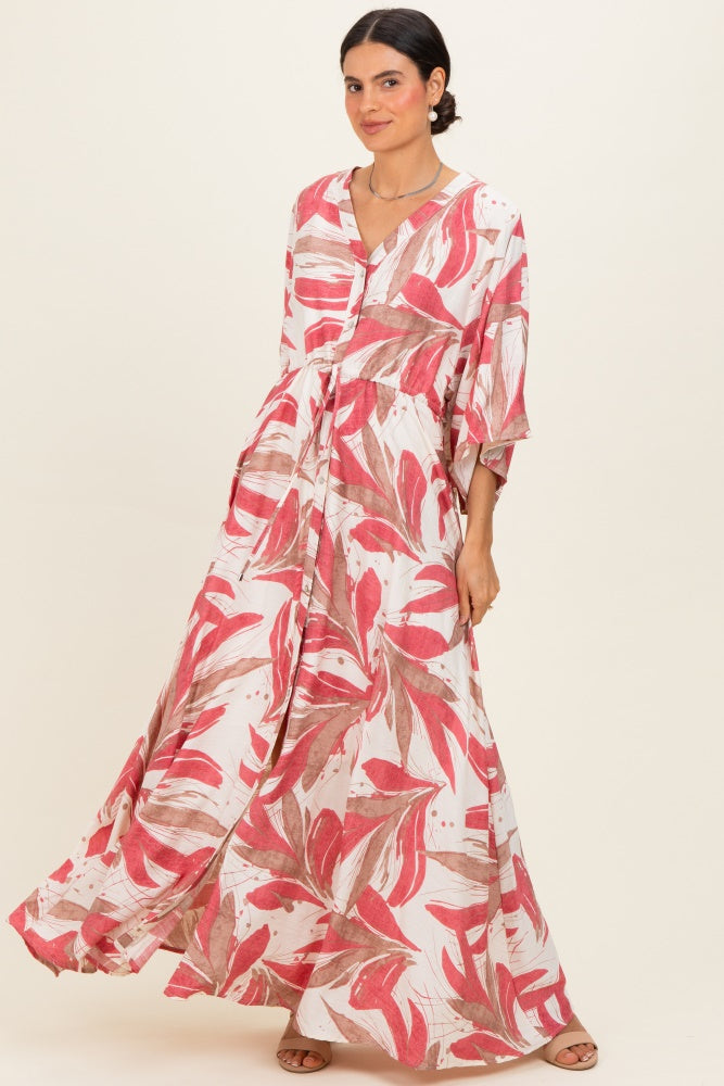 woman wearing a flowing maxi dress with a pink and red leaf print and a button-up front