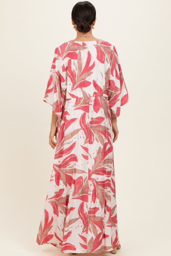 woman wearing a long patterned maxi dress with red and pink leaf designs, viewed from the back